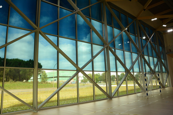 Large windows with geometric frames overlook a scenic outdoor view in a bright sports facility. - © Sage Glass