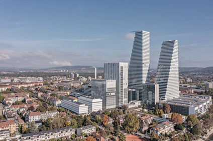 Aerial view of the Roche Tower complex in Basel, Switzerland, amidst cityscape and clear skies. - © René Dürr, Zurich