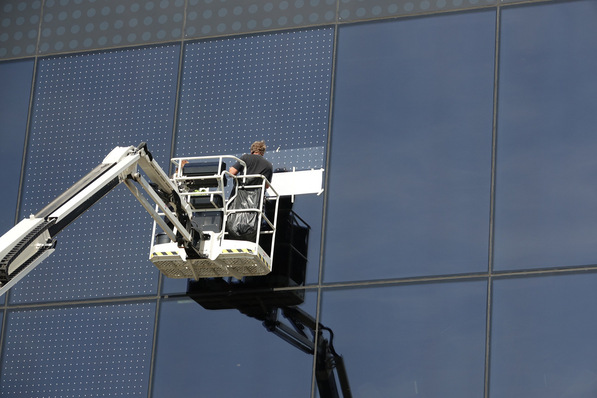 Two workers on a lift cleaning large glass windows of a modern building. - © Seen AG