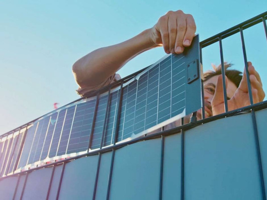 Person installing solar panels on a roof, bright blue sky in the background. - © Sunbooster