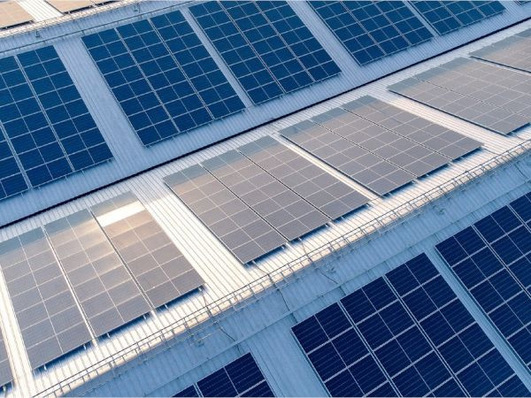 Rooftop with rows of solar panels under bright sunlight. - © Satinal