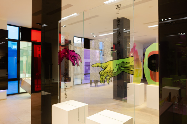 Bunte Handkunst auf Glasplatten in einer modernen Galerie mit hellen geometrischen Formen im Hintergrund. - © Lisec