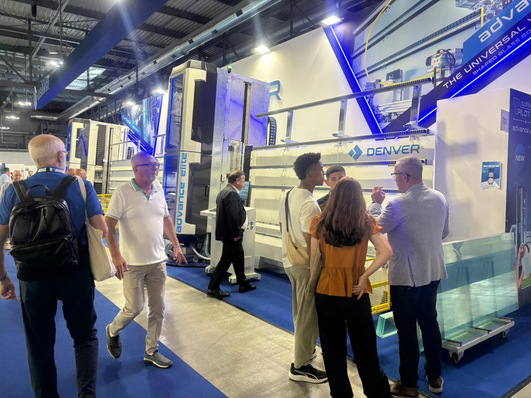 Auf einem Messestand interagieren Menschen und gehen an großen Industriemaschinen vorbei. - © Matthias Rehberger / GW