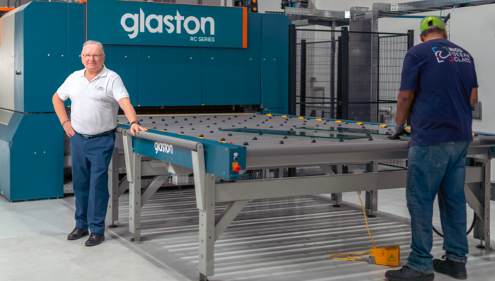 Zwei Männer arbeiten in einer modernen Produktionsstätte in der Nähe einer großen Industriemaschine der Glaston RC-Serie. - © Glaston