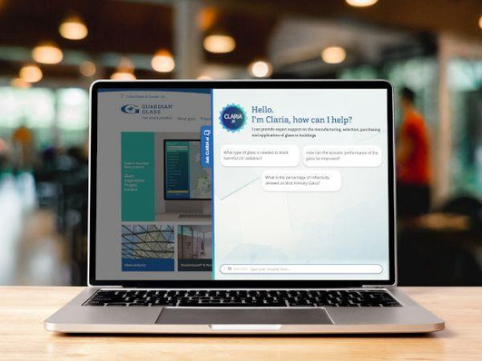 Laptop auf einem Tisch, der einen geteilten Bildschirm mit einer Website und einem Chatbot-Gespräch anzeigt. - © Guardian Glass