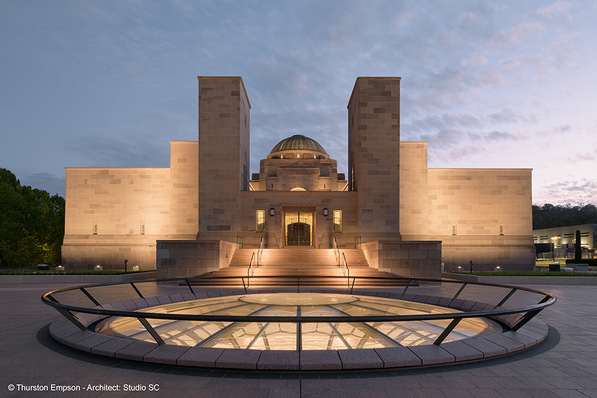 Das Australian War Memorial in der Abenddämmerung, warm beleuchtet mit einem glasüberdachten Rundbau im Vordergrund. - © Thurston Empson