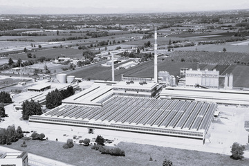 Luftaufnahme eines großen industriellen Fabrikkomplexes, umgeben von Feldern und Bäumen. - © Glass for Europe